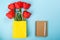 Spring tulips, notebook, pen on blue background. Flat lay with copy space. Red tulips in yellow shopping bag. Empty notebook for