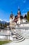 Spring view of Peles Castle with snow Bucegi Mountains in the background.