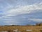 Spring village landscape: cloudy sky, dry grass and large white ice floes on the field