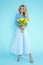 Spring Woman. Beauty Summer model girl with colorful clothes, holding a bouquet of spring flowers. Beautiful lady with yellow