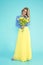 Spring Woman. Beauty Summer model girl with colorful clothes, holding a bouquet of spring flowers. Beautiful lady with yellow