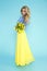 Spring Woman. Beauty Summer model girl with colorful clothes, holding a bouquet of spring flowers. Beautiful lady with yellow