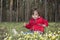 Spring in the woods on a flower meadow sits a little girl.