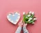 Springtime flat lay, female woman hands holding bunch of white tulips, Spring flowers. Lightboard in heart shape with illuminated