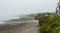 Springtime Nova Scotia coastline in June fog, people at base of cliff exploring the pebble beaches.