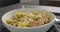 Sprinkle almond flakes on tagliatelle with chicken and pesto in bowl