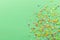 Sprinkle background with multicolored cake topping sprinkles scattered on pale green backdrop with space for text - top view