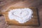 Sprinkled wheat flour with a painted heart on a wooden board and wooden table