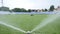 Sprinkler pours and mowing grass green football field grass