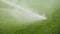 Sprinklers spraying water on the green grass in football field