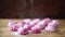 Sprinkling icing sugar on pink berry marshmallow on wooden table