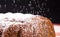 Sprinkling icing sugar powder over fresh sweet muffin cake close up on black background