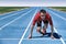 Sprinter athlete ready to start running race waiting at line on starting blocks on blue run tracks at outdoor stadium