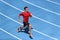Sprinter man running on blue tracks lanes in track and field stadium in high speed top view. Male athlete runner in intense sprint