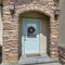 Square Arched stone exterior entryway and glass paned front door decorated with wreath