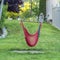 Square Backyard of home with red hammock hanging on metal pole and lush green grasses