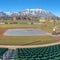 Square Baseball field with green tiered seating against mountain and vibrant blue sky