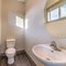 Square Bathroom of home with free standing sink round mirror toilet and wooden floor