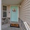 Square Bay window pastel green front door and open porch at the facade of charming home