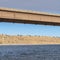 Square Beam bridge with abutment foundation against rugged land and cloudy sky