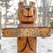 Square Bear wood sculpture on a landscape covered with powdery white snow in winter