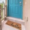 Square Blue green door of a home with doormat railing and stone pillar at the entrance