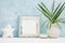 Square blue Photo frame mock up with green tropical plants in vase, ceramic star and candle on shelf. Scandinavian style