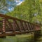 Square Bridge with latticed metal guardrail over a calm stream viewed on a sunny day