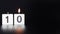 A square candle saying the number 10 being lit and blown out on a dark black background celebrating a birthday or anniversary