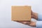 Square cardboard box in male hands. Delivery of parcels. Side view