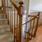 Square Carpeted staircase with brown handrail inside a house with shiny wooden floor