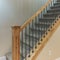 Square Carpeted stairs with wooden handrailing and wrought iron baluster