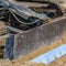 Square Close up of a metal grader blade against the ground with brown soil