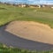 Square Close up view of a sand trap at a sunny golf course with houses in the distance