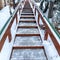 Square crop Focus on stairs with grate treads and metal handrails against snow covered hill