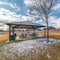 Square crop Pavilion with tables benches and melted snow against homes and cloudy blue sky