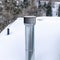 Square crop Shiny metal chimney vent pipe on the roof of home covered with snow in winter