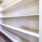 Square crop Small walk in closet with empty long cabinet shelves under slanted ceiling