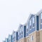 Square crop Snowy gable roofs at the facade of townhome with brick wall and vertical siding