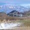 Square crop Snowy hilly terrain with houses against sunlit frosted mountain in winter