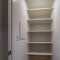 Square crop Walk in closet or pantry with empty wall shelves seen through open hinged door