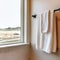 Square crop White towel hanging on black rod mounted on the bathroom wall with tiles