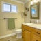 Square Double vanity with wooden cabinets inside a bathroom with small window