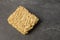 Square dry egg noodles in a briquette on a gray stone marble slate background