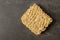Square dry egg noodles in a briquette on a gray stone marble slate background