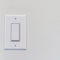 Square Electrical rocker light switch with flat broad lever on white interior wall