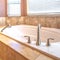 Square Elevated built in bathtub against the bay windows with blinds of a bathroom