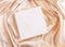 Square envelope on beige silky fabric drapery top view, greeting or wedding mockup