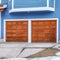 Square Exterior of home with blue wall and attached two car garage with brown doors