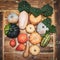 Square flatlay, various sorts of pumpkin squash on wooden table with green leaves